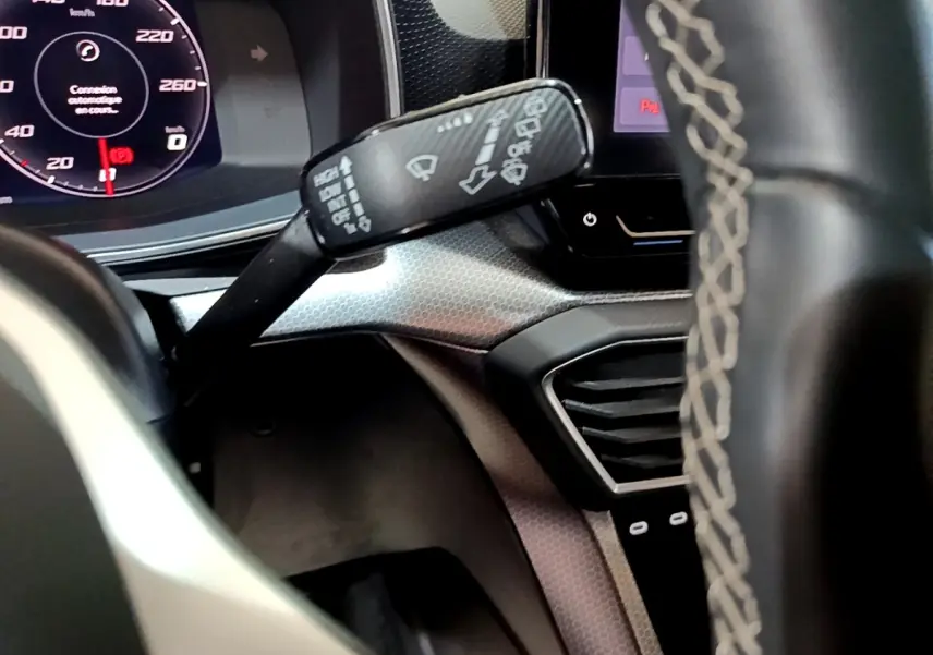Gros plan intérieur sur le combiné d'instruments et la commande d'essuie-glace du SEAT Leon 2023, volant partiellement visible.