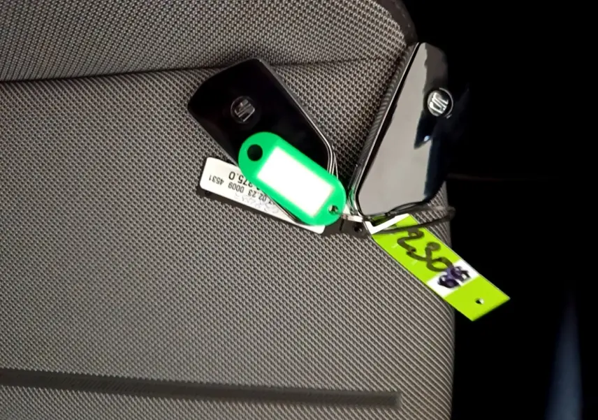 Clé de voiture SEAT LEON 2023 posée sur un siège tissu gris clair, avec porte-clés vert fluo visible.