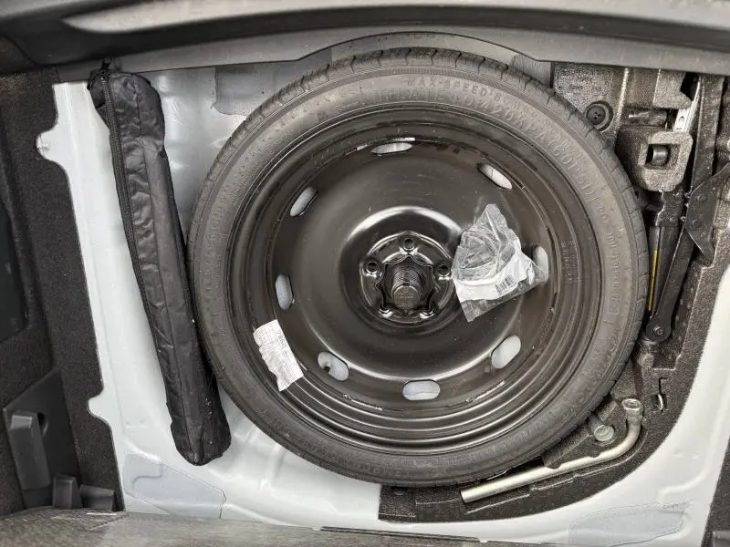 Vue rapprochée de la roue de secours noire dans le coffre d’un CUPRA Formentor blanc Nevada métallisé 2025.