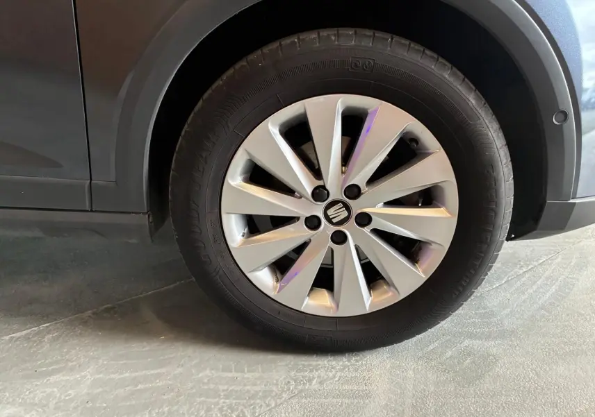 Gros plan sur la roue avant gauche du SEAT Arona gris foncé, avec jante alliage et logo central visible.