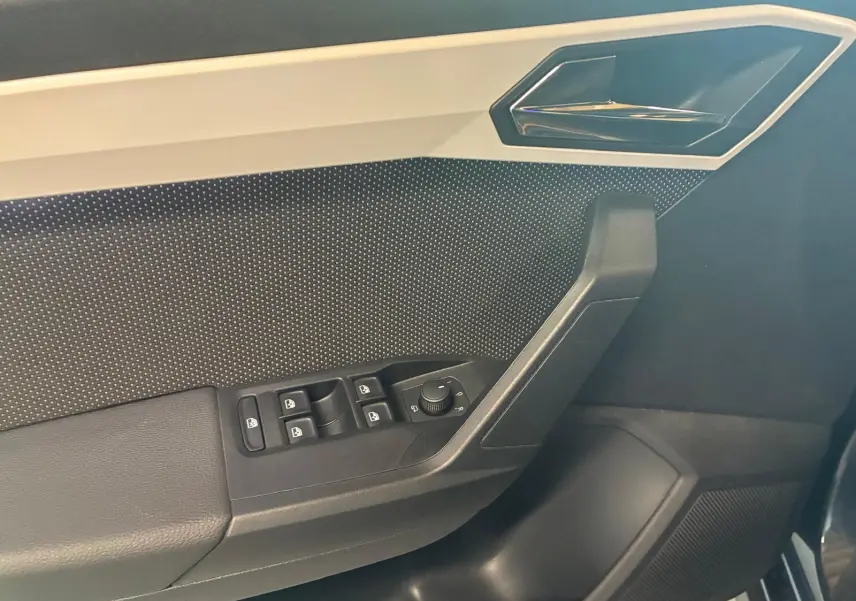 Détail de la porte avant gauche du SEAT Arona gris foncé 2021, avec commandes des vitres et poignée intérieure chromée.