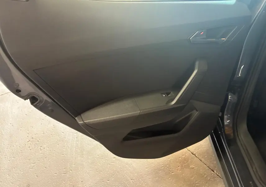 Vue rapprochée de la porte arrière droite intérieure d'un SEAT Arona gris foncé, avec panneau noir et commande de fenêtre.