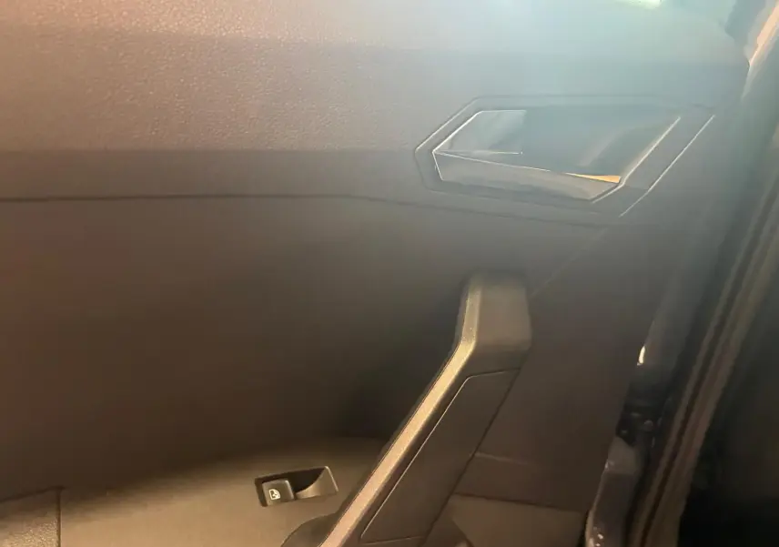 Intérieur côté gauche de la porte d’une SEAT Arona gris foncé, avec poignée et commande de vitre électrique.