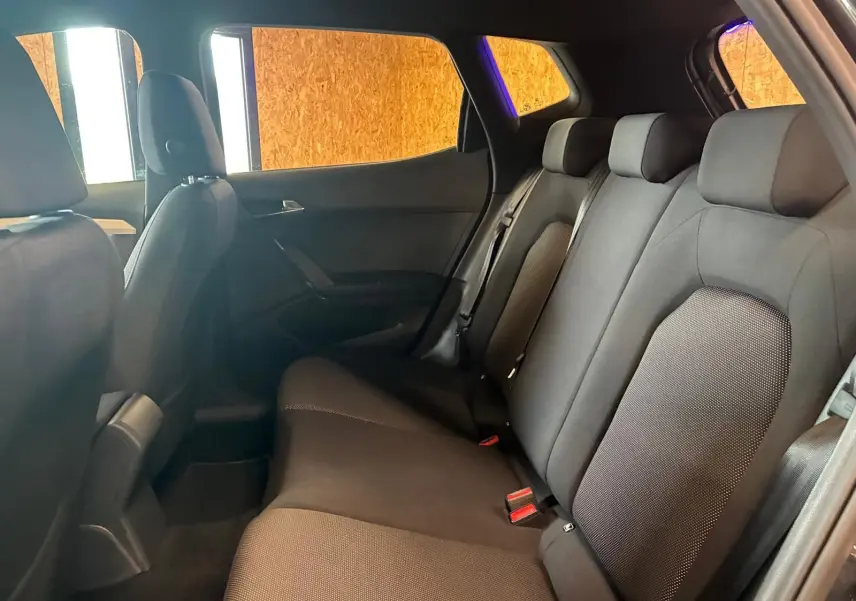 Vue intérieure côté droit des sièges arrière en tissu noir du SEAT Arona gris foncé 2021, ambiance sobre et lumineuse.