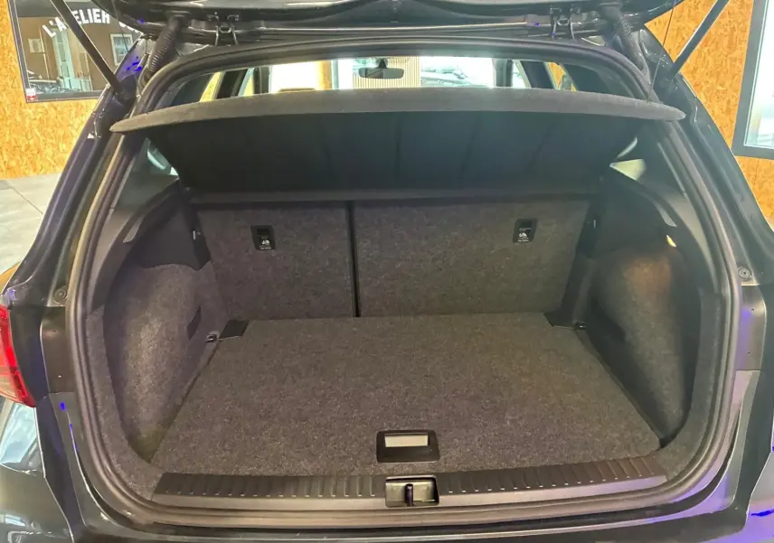 Coffre ouvert vu de l'arrière d'un SEAT Arona gris foncé, montrant un espace de chargement propre et vide.