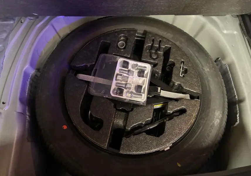 Roue de secours avec outils de changement rangés dans le coffre d'un SEAT Arona gris foncé.