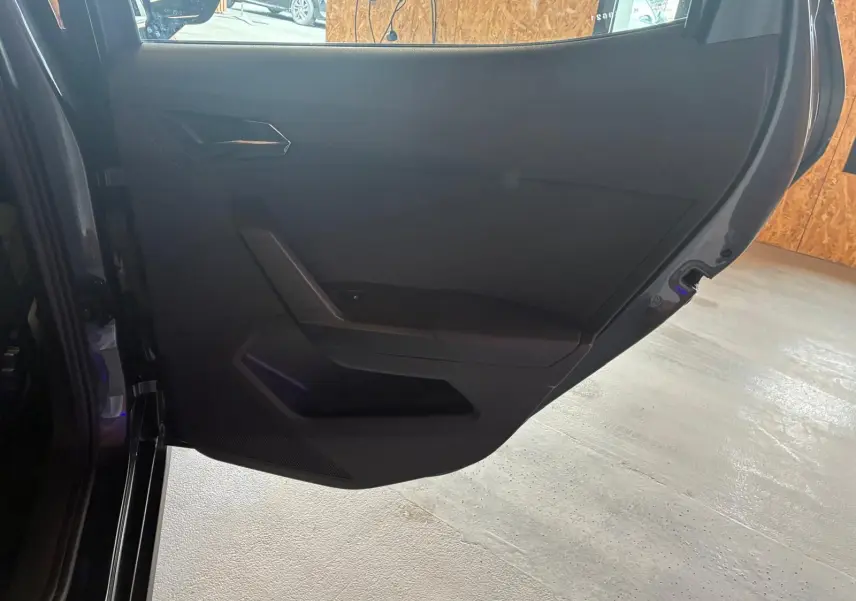 Vue intérieure de la porte arrière gauche du SEAT Arona gris foncé, avec garniture noire et poignée intégrée.