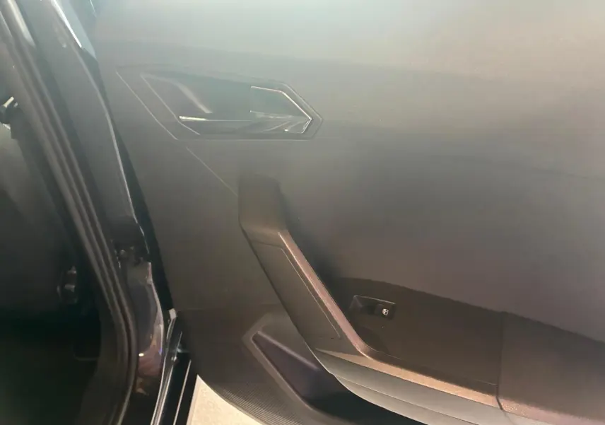 Vue intérieure côté gauche de la porte arrière d’un SEAT Arona gris foncé avec garniture noire et poignée angulaire.