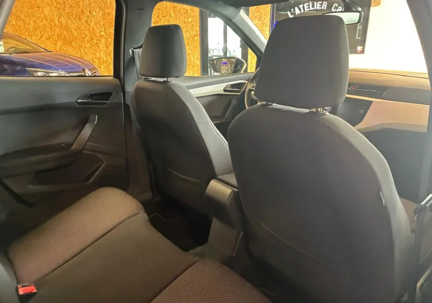 Vue intérieure arrière du SEAT Arona gris foncé, montrant les sièges en tissu noir et la planche de bord côté passager.