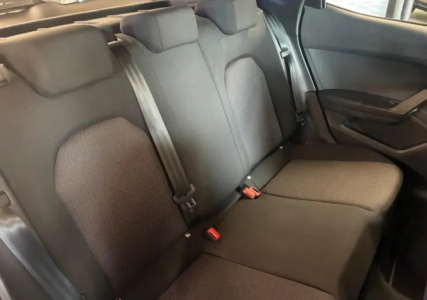 Vue intérieure sur les sièges arrière en tissu noir du SEAT Arona 1.0 TSI 110 XCELLENCE, avec ceintures de sécurité visibles.