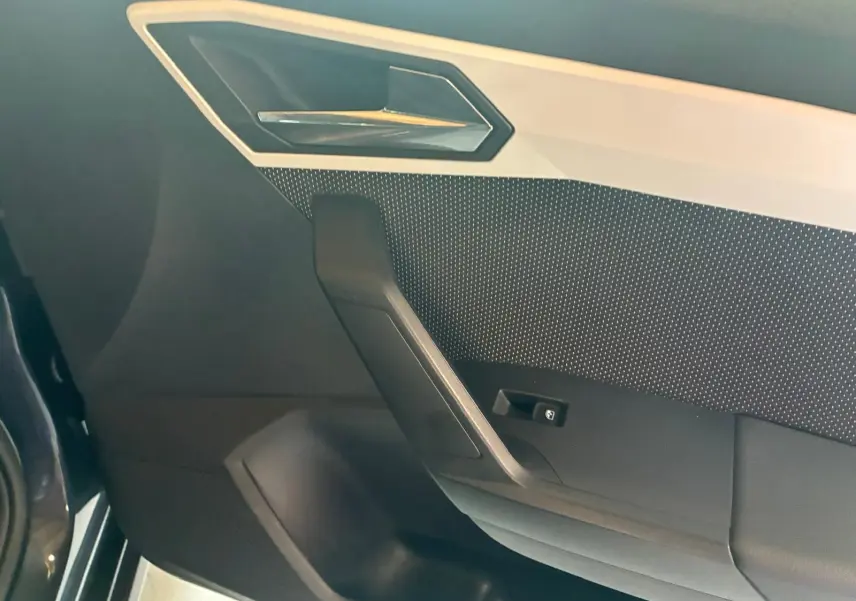 Détail de la porte intérieure côté conducteur du SEAT Arona gris foncé, avec poignée et bouton de commande de vitre.