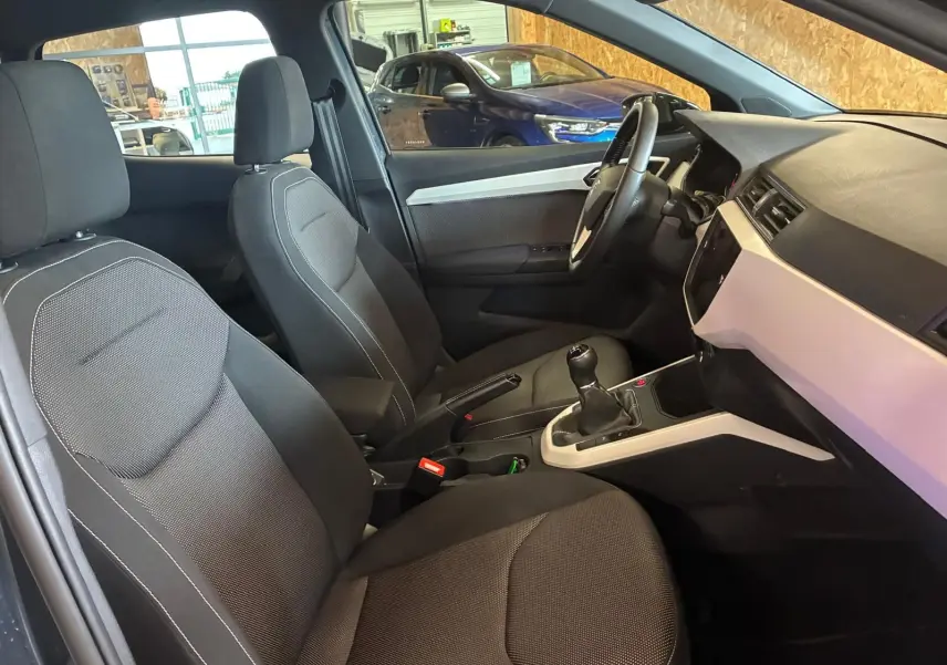 Vue intérieure côté conducteur du SEAT Arona gris foncé 2021, mettant en valeur les sièges tissu noirs et la boîte manuelle.