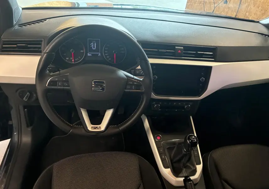 Vue intérieure frontale du tableau de bord noir et gris du SEAT Arona 1.0 TSI 110 XCELLENCE avec boîte manuelle.
