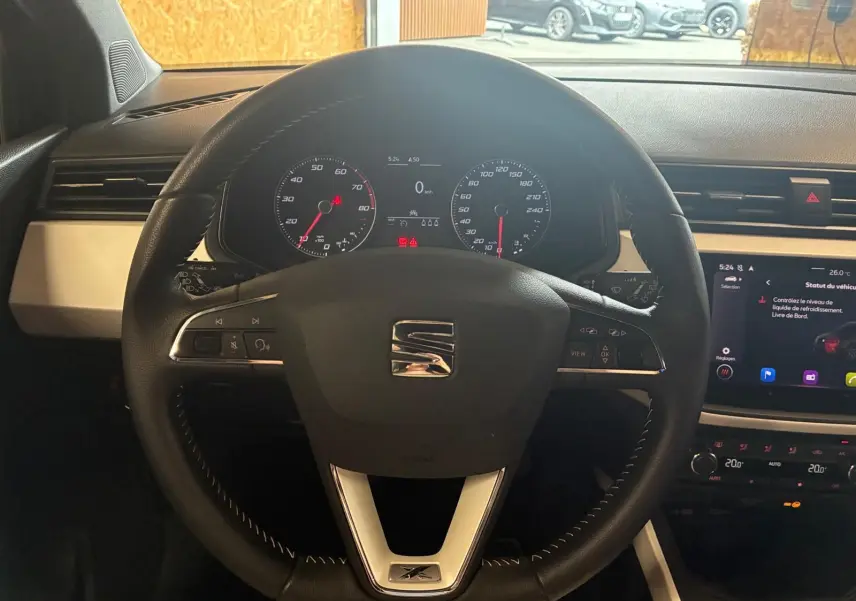 Vue centrée sur le volant noir du SEAT Arona gris foncé 2021, avec tableau de bord et écran tactile visibles.