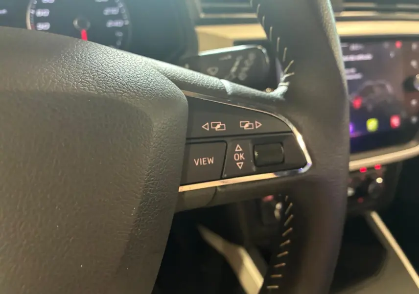 Gros plan sur les commandes gauche du volant noir du SEAT Arona 2021, avec boutons de navigation et affichage.