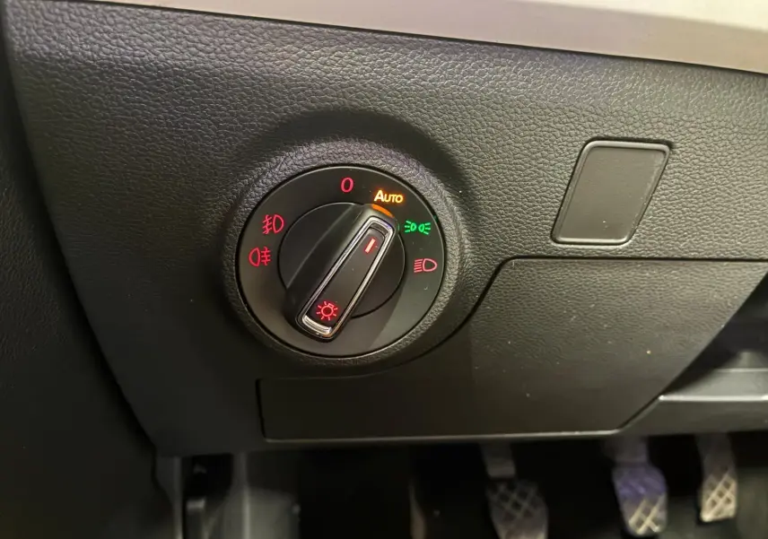 Gros plan sur le bouton de commande des phares du tableau de bord noir du SEAT Arona gris foncé, version 1.0 TSI 110 XCELLENCE.