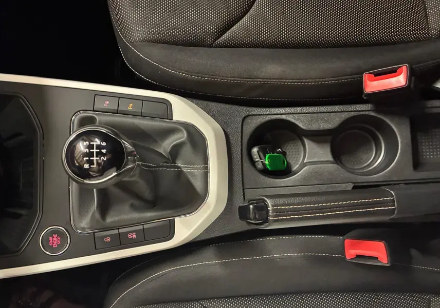 Vue rapprochée de la console centrale du SEAT Arona gris foncé, montrant le levier de vitesse manuel et les sièges en tissu noir.