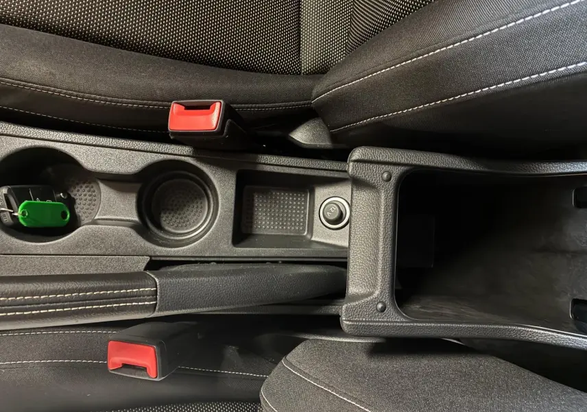 Vue plongeante sur la console centrale noire en tissu du SEAT Arona gris foncé, avec porte-gobelets et accoudoir ouvert.