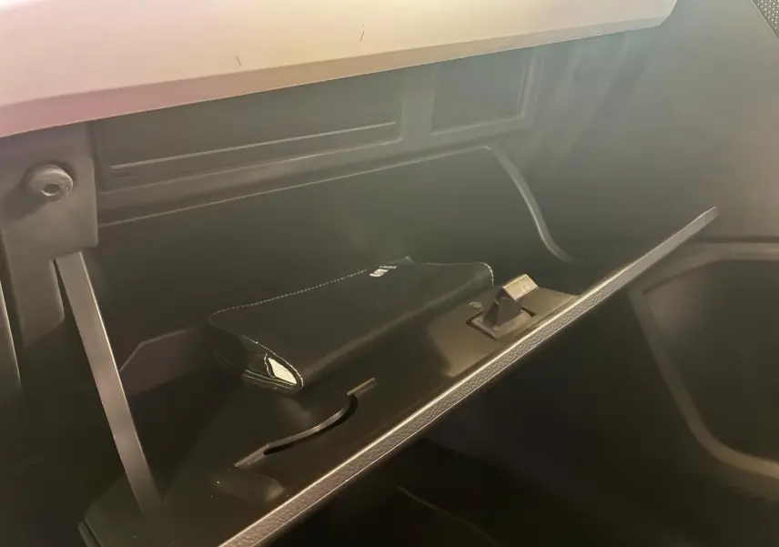 Gros plan de la boîte à gants ouverte du SEAT Arona 1.0 TSI 110 Xcellence, intérieur noir avec pochette visible.
