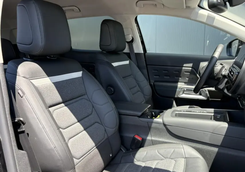 Vue intérieure côté conducteur du Citroën C5 Aircross Hybrid 2025, sièges tissu noir et gris avec surpiqûres.
