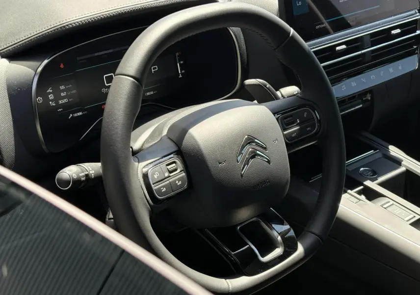 Vue rapprochée du volant noir cuir du Citroën C5 Aircross Hybrid 2025 avec commandes intégrées et tableau de bord numérique.