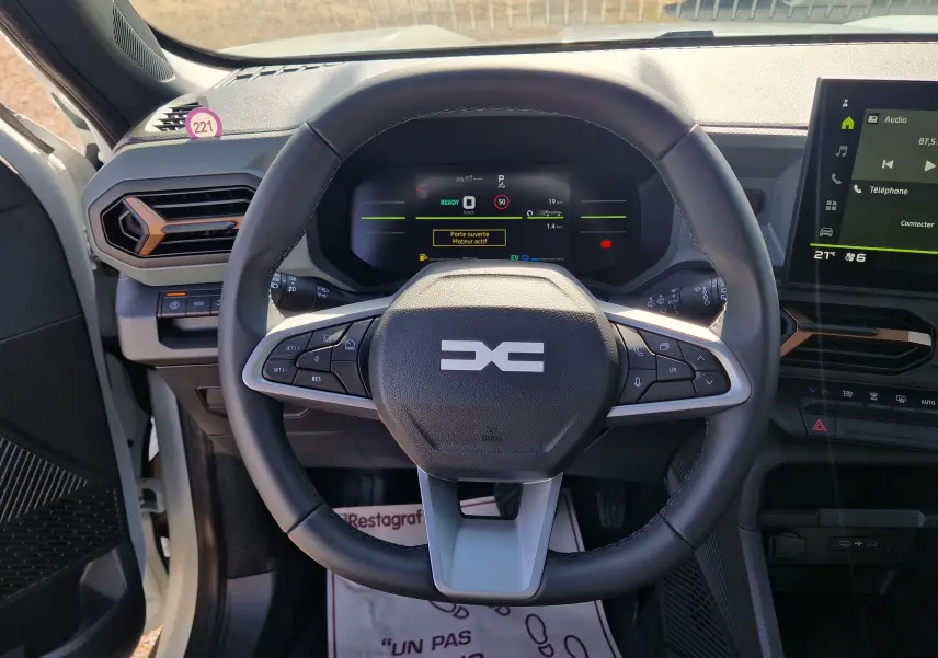 Vue intérieure centrée sur le volant du Dacia Duster blanc 2026, avec tableau de bord numérique et écran tactile visible.