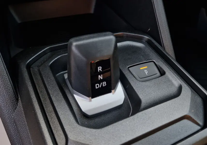 Gros plan sur le levier de vitesses automatique noir et gris du Dacia Duster blanc 2026 avec bouton de parking éclairé.