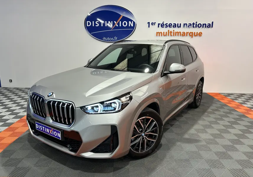 BMW X1 sDrive20d M Sport 2024 en gris Spacesilber, vue 3/4 avant avec phares LED allumés dans un showroom