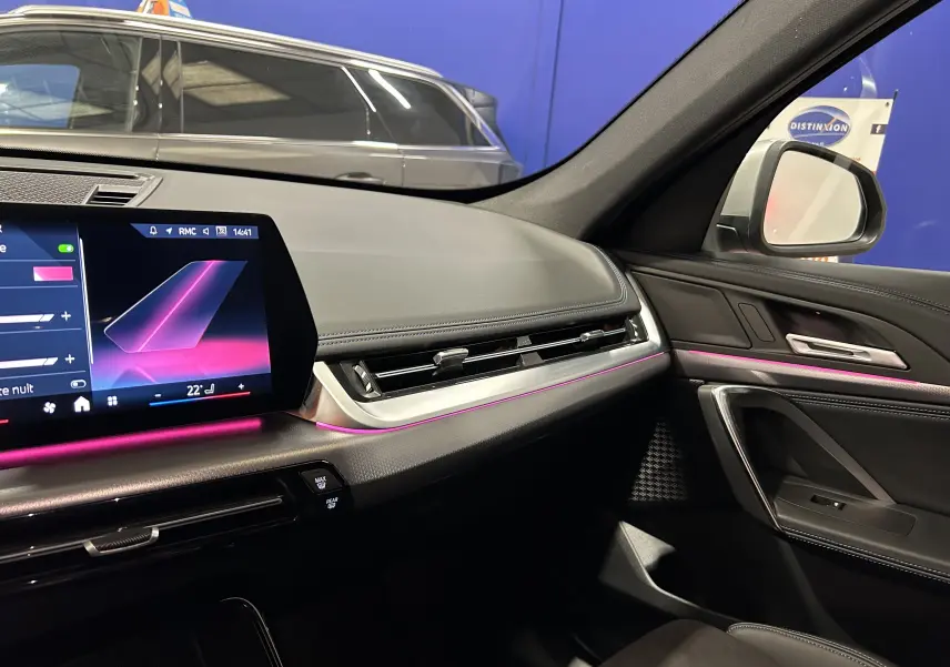 Tableau de bord et porte côté droit du BMW X1 2024 M Sport avec éclairage d'ambiance violet et écran tactile.