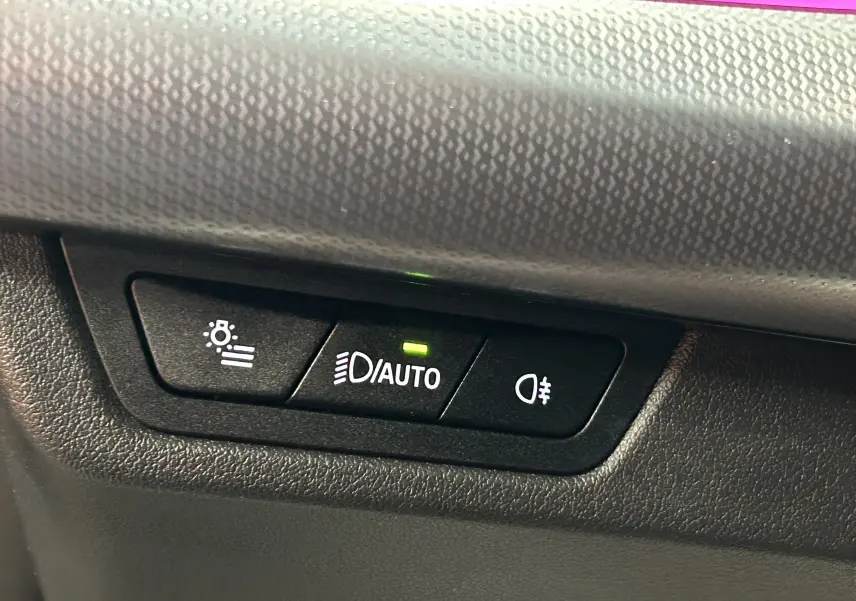 Boutons de commande des feux automatiques et antibrouillard sur tableau de bord noir texturé d'un BMW X1 Spacesilber 2024.