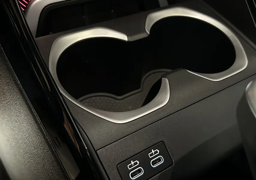 Gros plan sur la console centrale noire du BMW X1 2024 avec porte-gobelets et deux ports USB-C lumineux.