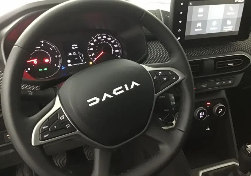 Vue rapprochée du volant noir de la Dacia Sandero Stepway 2025 avec tableau de bord et écran tactile visible.