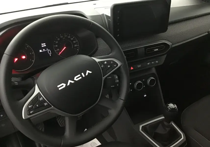 Vue intérieure centrée sur le volant et la console centrale d'une Dacia Sandero Stepway 2025 avec boîte manuelle.