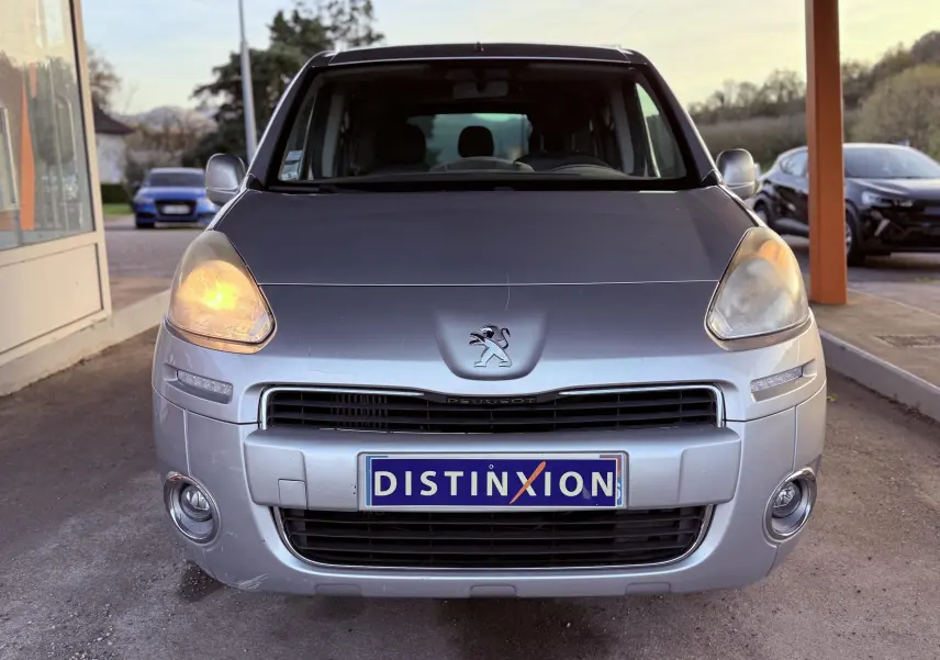 Vue avant d'un Peugeot Partner Tepee gris 2014 avec phares allumés et plaque Distinxion visible.