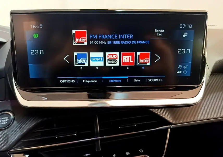 Écran tactile central du tableau de bord Peugeot 2008 gris clair, affichant les radios FM avec interface moderne.