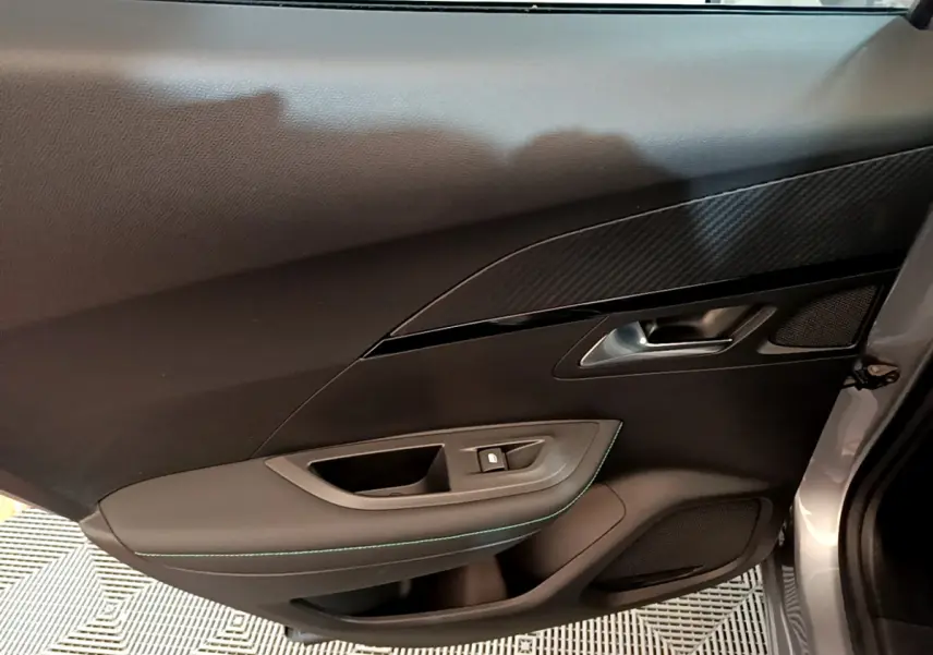 Vue intérieure côté gauche de la porte avant gris clair du Peugeot 2008 avec insert décoratif noir et bouton de verrouillage.