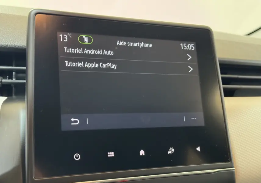 Écran tactile central du tableau de bord de la Renault Clio Business blanc, affichant tutoriels Android Auto et Apple CarPlay.
