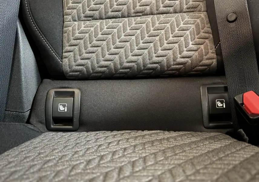 Gros plan sur les fixations Isofix entre les sièges arrière gris texturés de la Renault Clio Business blanche 2023.