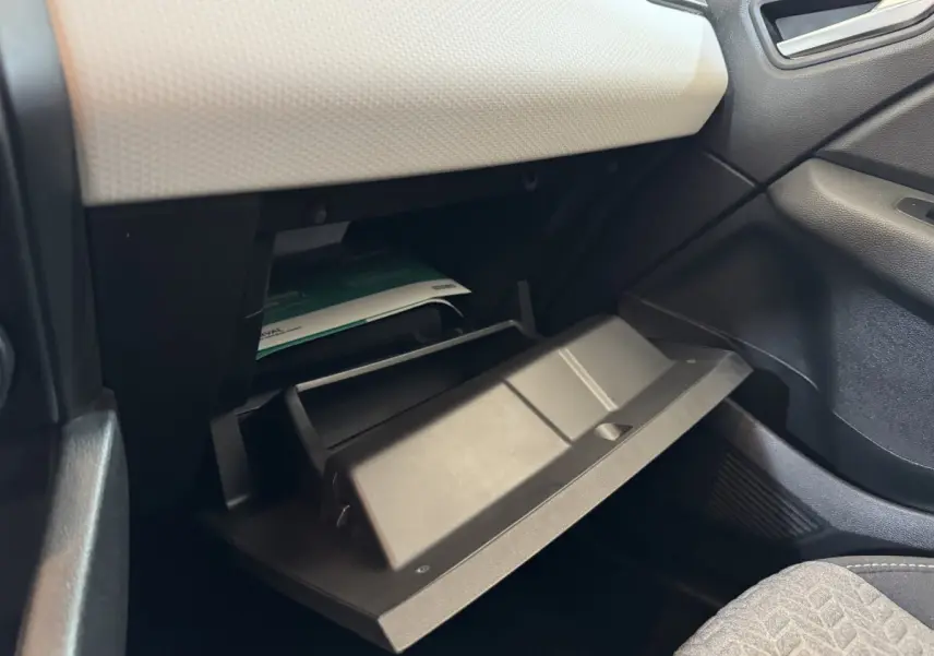 Gant de rangement ouvert côté passager dans l'habitacle d'une Renault Clio Business blanc, avec tableau de bord clair.