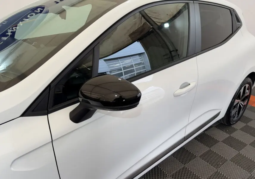 Vue latérale droite rapprochée d'une Renault Clio Business blanche avec rétroviseur noir brillant et jante noire.