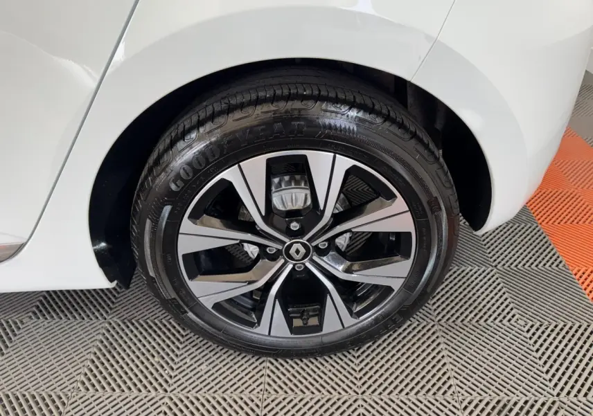 Gros plan sur la roue arrière droite d'une Renault Clio blanche 2023 avec jante alliage noire et argentée.