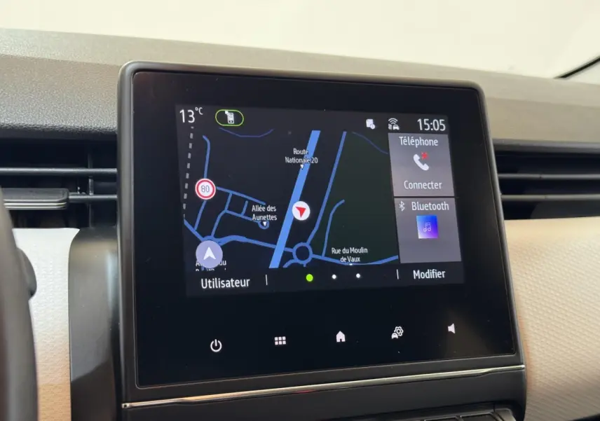 Écran tactile central du tableau de bord de la Renault Clio Business blanc, affichant la navigation GPS et options Bluetooth.