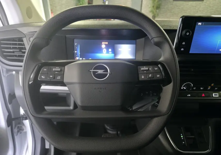 Vue frontale du volant noir avec logo Opel, tableau de bord numérique et écran tactile dans l'habitacle blanc du Vivaro 2025.
