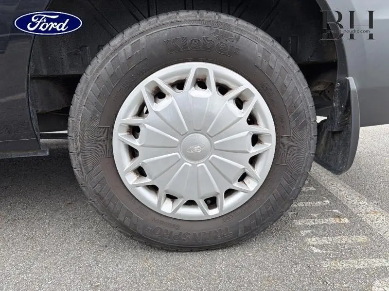 Gros plan sur la roue avant droite du Ford Transit Custom noir, avec enjoliveur argenté et pneu Kleber.