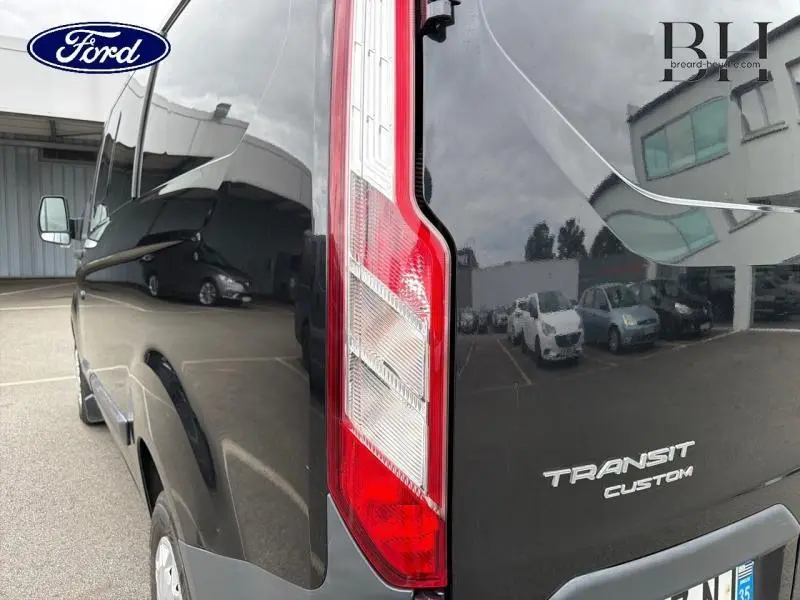 Vue arrière côté droit du fourgon Ford Transit Custom noir avec feux arrière et logo visible.