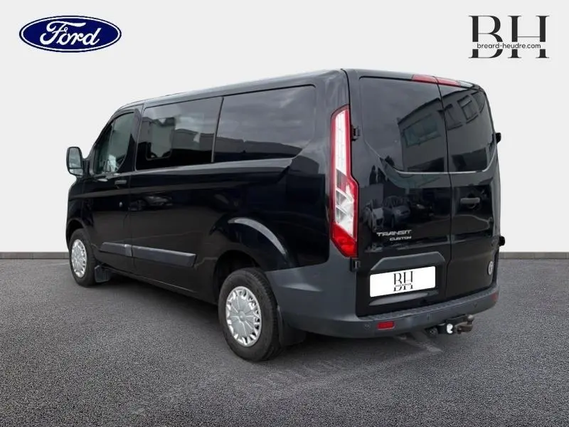 Ford Transit Custom noir vu en 3/4 arrière droit, avec portes arrière doubles et vitres teintées.