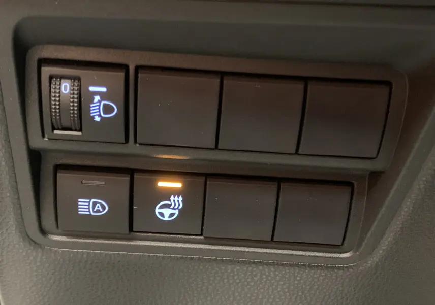 Gros plan sur les commandes de réglage des phares et du volant chauffant de la Toyota Yaris blanche.