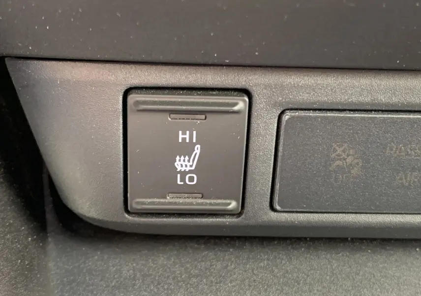 Gros plan sur le bouton de réglage de chauffage de siège avec options Hi et Lo dans une Toyota Yaris blanche.