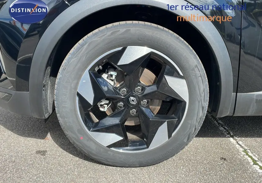 Gros plan sur la roue avant gauche du Renault Captur noir étoile métal avec jante noire et grise à design géométrique.