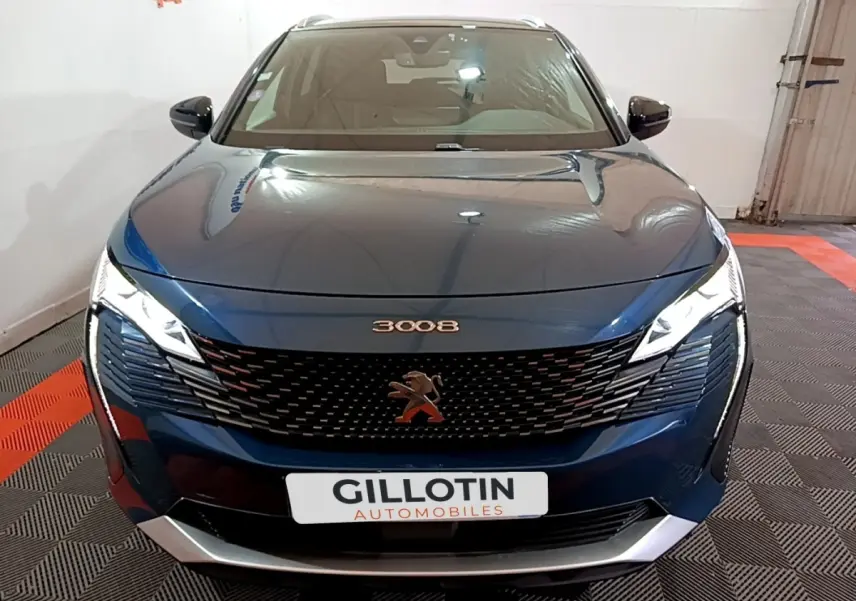 Vue avant d'un Peugeot 3008 bleu métallisé avec calandre noire et phares LED allumés en intérieur showroom.
